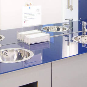 Waschtisch mit drei modernen Edelstahl-Waschbecken und glänzender blauer Oberfläche.